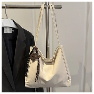 Détail du sac cabas blanc cassé avec breloque biscuit marron et cordon sur cintre