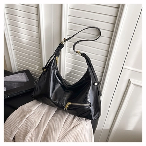 Detail of black patent leather hobo bag with gold hardware on a modern minimalist background