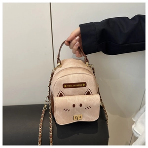 Close-up of beige leather mini backpack featuring metal chain and animal motif