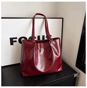 Macro view of burgundy patent leather texture and silver bow detail on tote bag