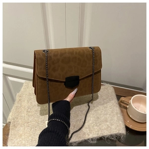 Détail du sac bandoulière léopard avec fermoir en métal noir sur fond de fausse fourrure