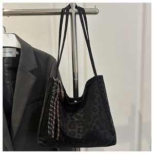Détail du sac hobo en daim noir à motif léopard avec pendentif tissé et perles en bois