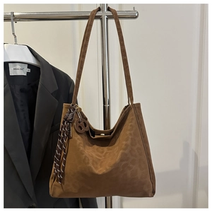 Détail du sac cabas en suédine marron avec imprimé léopard discret et pompon tressé