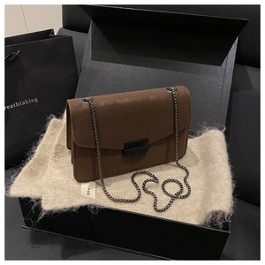 Détail du sac bandoulière en daim marron avec fermoir noir mat et bandoulière chaîne