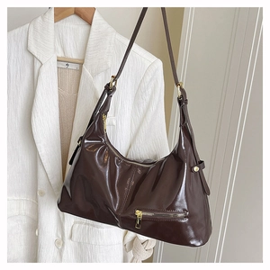 Detail of glossy brown leather tote bag with smooth zipper and golden hardware accents