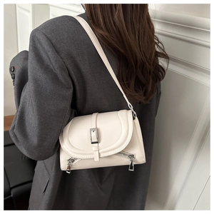 Close-up of a cream-colored leather shoulder bag with metallic buckle and zipper details