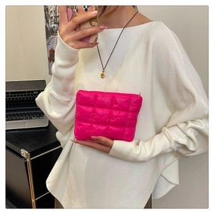 Close-up of bright pink quilted makeup bag with zipper held by a model in a casual setting
