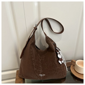 Detail of dark brown leopard embossed hobo tote bag with a cute dog charm on a wooden table