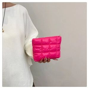 Macro detail of vibrant hot pink quilted makeup bag with soft padded check texture