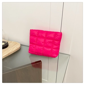 Detailed view of bright pink quilted makeup bag with soft padded texture and gold zipper