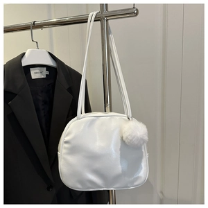 Detail of white glossy PU shoulder bag with soft curves and a cute plush pom pom charm