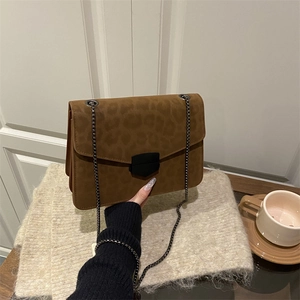 Sac bandoulière imprimé léopard avec chaîne et boucle sur un fond rustique chic