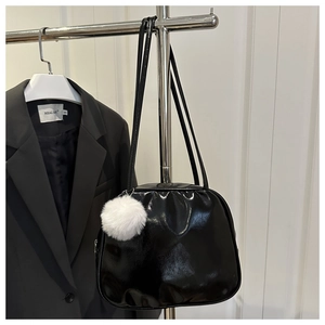 Close-up of a black glossy PU leather travel toiletry bag with a white plush ball charm