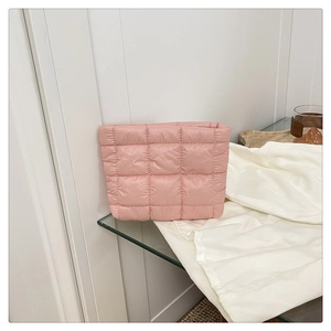 Detailed close-up of pink quilted makeup bag showing the soft fabric texture on glass surface
