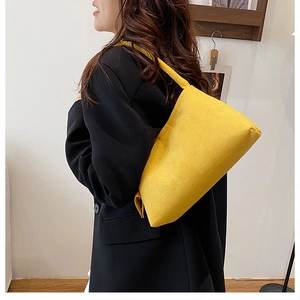 Detail view of bright yellow wool shoulder bag texture and stitching on a model