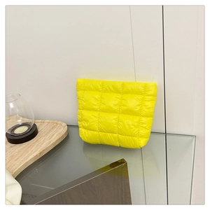 Detailed shot of yellow quilted checkered makeup bag on a modern marble tray