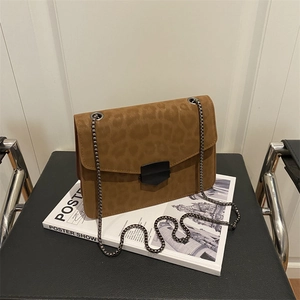Sac à chaîne léopard marron en daim mat avec fermoir métallique sur un magazine