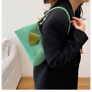 Detail of green suede shoulder bag with olive mini pouch on a black suit model