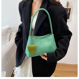 Close-up of mint green suede moon bag with a lime green mini charm on a model
