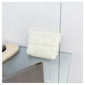 Detailed close-up of off-white quilted puffer handbag with a soft padded grid texture
