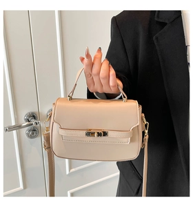 Detail of beige crossbody bag featuring horizontal belt strap and gold twist lock closure