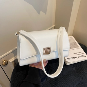 Classic white leather underarm bag with gold metal clasp on a textured black cushion