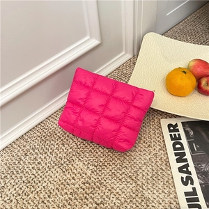 Fuchsia quilted puffy makeup bag in glossy finish on a stylish minimalist background