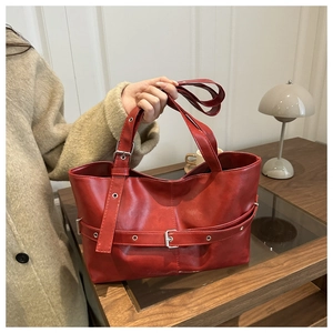 Close-up of red tote bag featuring premium leather texture and silver buckle detail