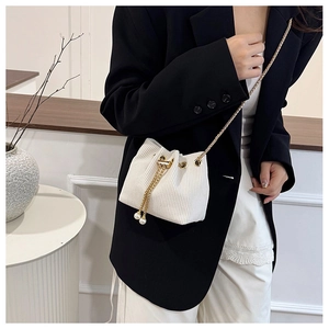 Detail of white corduroy drawstring bucket bag with pearl charms and gold chain strap