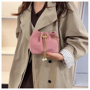 Detailed shot of pink corduroy bucket bag with pearl drawstring and golden chain strap