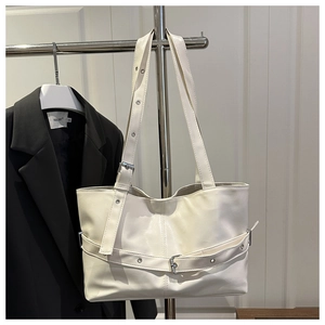 Detail of white leather tote bag with silver eyelet belts and adjustable shoulder strap