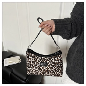 Détail du sac à bandoulière en toile léopard avec bordures en cuir noir et logo