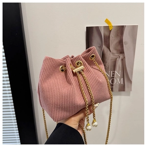 Detail of pink corduroy drawstring bucket bag with gold chain and large pearl accents