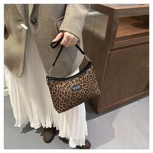 Detail of leopard print shoulder bag featuring black leather strap and fashion label
