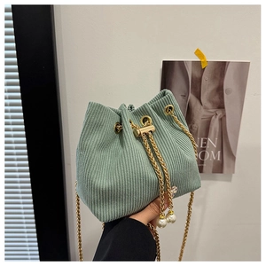 Detail of light green corduroy bucket bag with pearl drawstring and golden chain strap