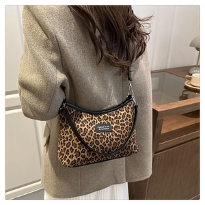 Close-up of leopard print baguette bag with black leather trim and woven logo label