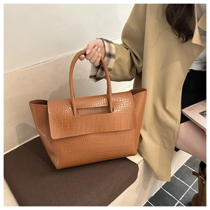 Detail of brown crocodile pattern leather tote bag with elegant long handles and wide opening
