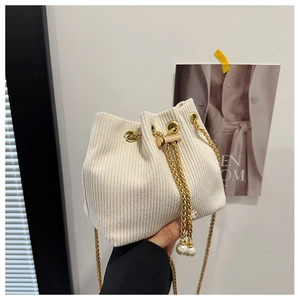 Detail of white corduroy bucket bag featuring drawstring closure and pearl accents