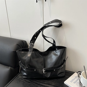 Black glossy tote bag with buckle details and silver hardware in a modern setting