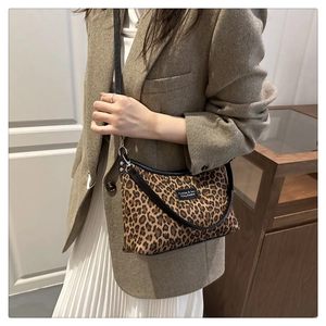 Close-up of leopard print tote bag with black leather trim and woven logo detail