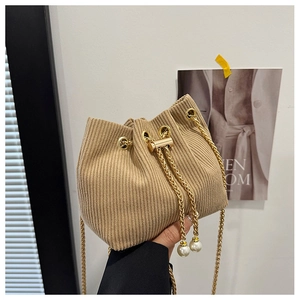 Detail of beige corduroy bucket bag featuring gold drawstring lock and white pearl charms