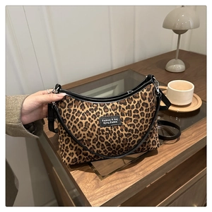 Close-up of leopard print handbag with black leather trim on a wooden tabletop