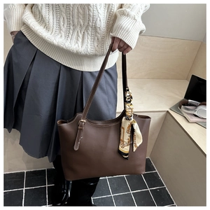 Detail of dark brown tote bag with white stitching and printed silk scarf on handle