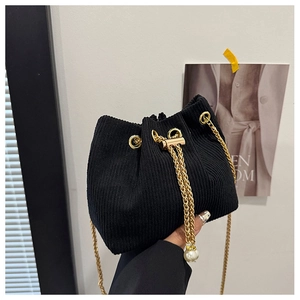 Detail of black corduroy bucket bag with gold chain strap and pearl bead charm
