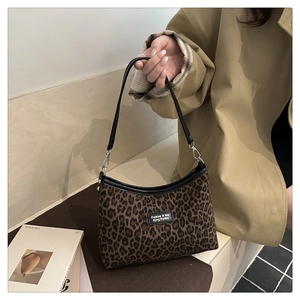 Detail of leopard print handbag showing fabric texture and leather shoulder strap