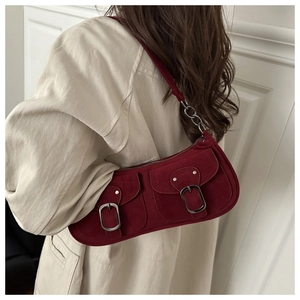 Detail der weinroten Wildleder-Schultertasche mit silbernen Schnallen zum beigen Mantel