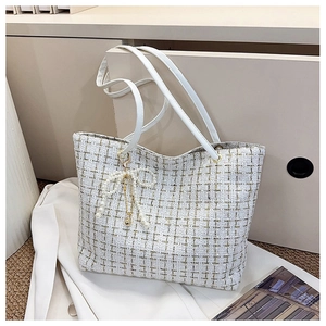Detail der weißen Tweed-Tasche mit Goldfäden und Perlen-Schleifenanhänger Accessoire