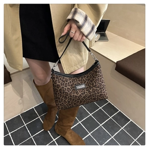 Leopard print handbag detail featuring black straps and metallic brand plate on the front