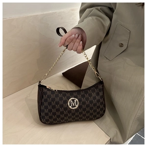 Dettaglio della borsa sottobraccio in pelle marrone vintage con motivo M e catena oro