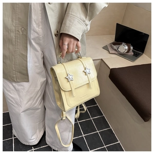 Detail of a creamy yellow mini leather backpack with silver stars held in a lifestyle setting
